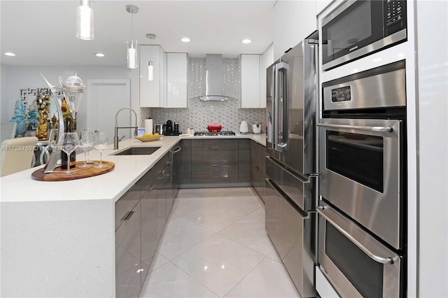 kitchen with sink, light tile patterned floors, white cabinetry, stainless steel appliances, and wall chimney exhaust hood