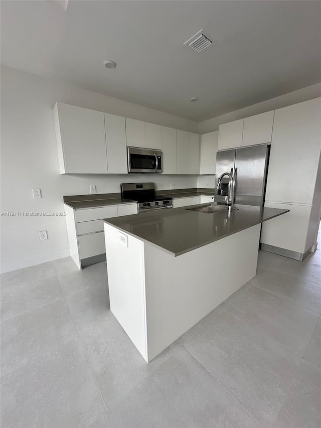 kitchen featuring white cabinetry, stainless steel appliances, a center island with sink, and sink