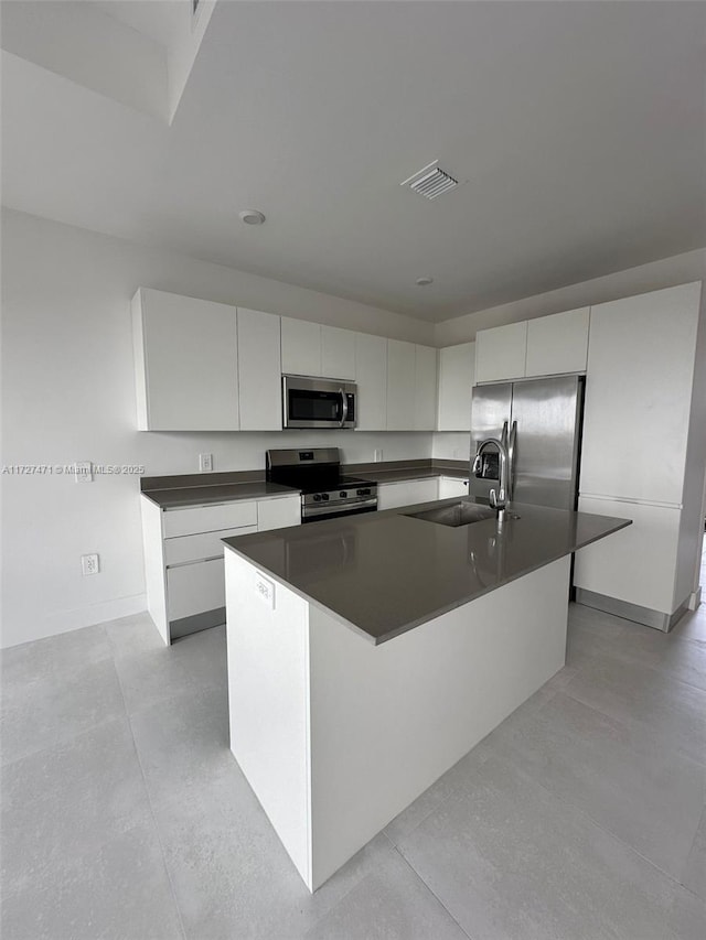 kitchen with sink, white cabinetry, appliances with stainless steel finishes, and a center island with sink