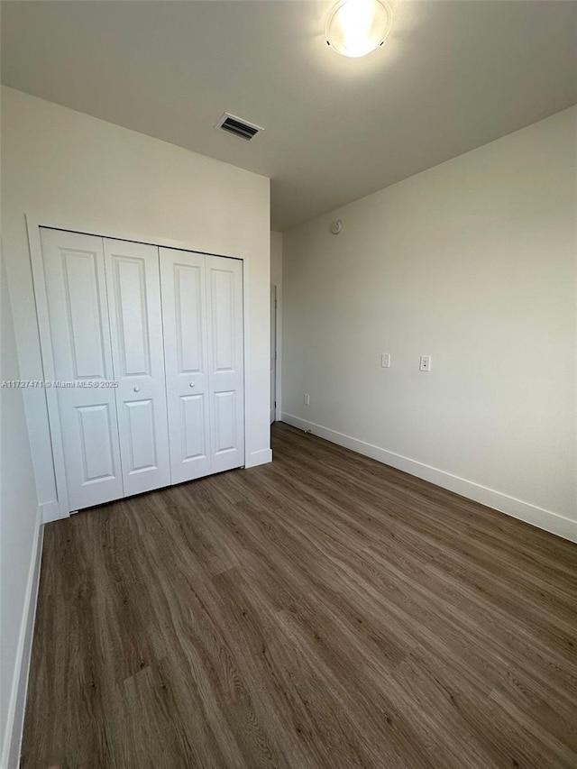 unfurnished bedroom featuring dark hardwood / wood-style floors and a closet