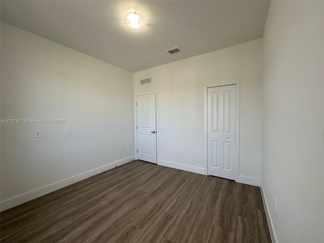 unfurnished bedroom featuring dark wood-type flooring and a closet