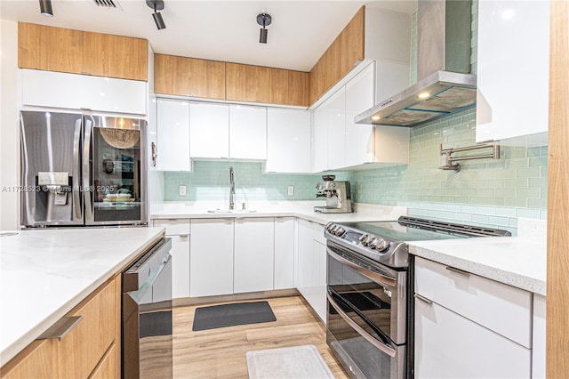 kitchen featuring white cabinets, sink, wall chimney range hood, and stainless steel appliances