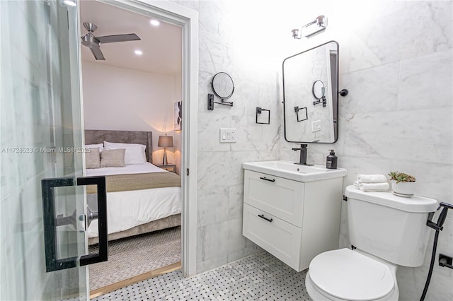 bathroom with toilet, vanity, tile walls, and ceiling fan