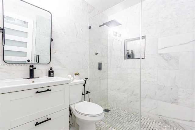 bathroom featuring tile walls, toilet, vanity, and a tile shower