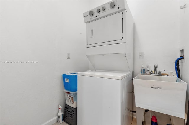 laundry area featuring stacked washer / drying machine and sink