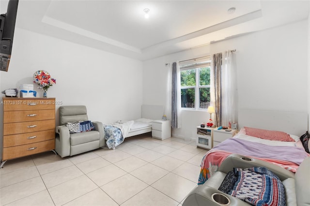 bedroom featuring light tile patterned flooring and a tray ceiling