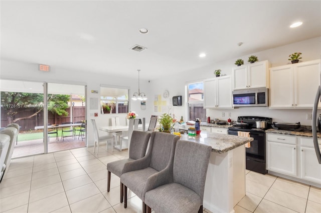 kitchen featuring pendant lighting, white cabinets, black electric range, light stone counters, and light tile patterned floors