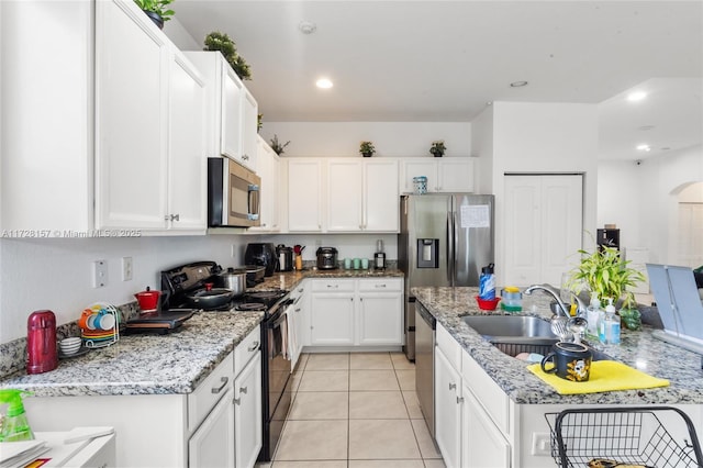 kitchen with sink, light tile patterned flooring, stainless steel appliances, white cabinets, and light stone counters