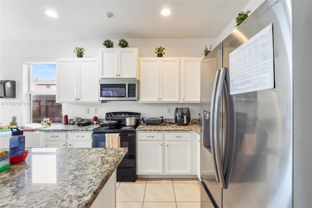 kitchen with light tile patterned flooring, appliances with stainless steel finishes, white cabinets, and light stone countertops