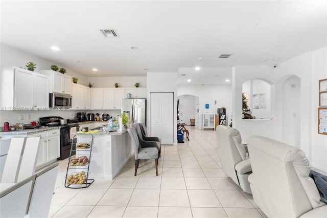 kitchen with white cabinetry, stainless steel appliances, light stone counters, and a center island