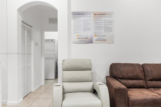 sitting room featuring stacked washer and dryer and light tile patterned floors