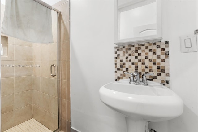 bathroom featuring sink, backsplash, and a shower with door