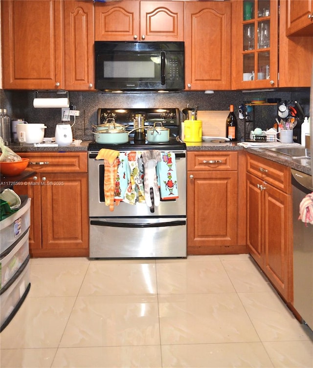 kitchen with appliances with stainless steel finishes, light tile patterned floors, and decorative backsplash