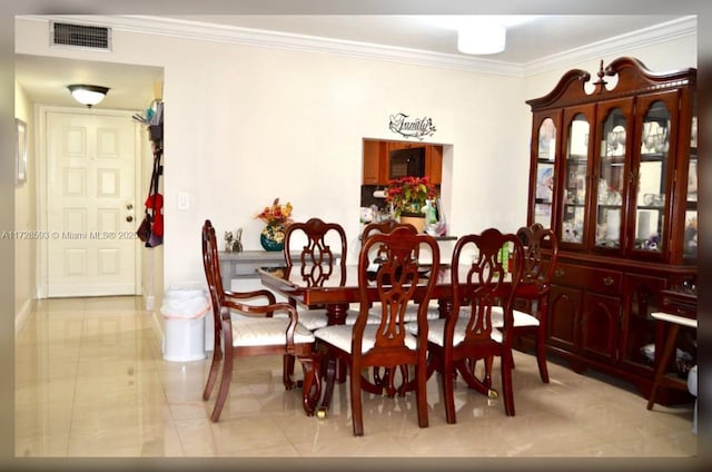 dining room featuring crown molding and light tile patterned floors