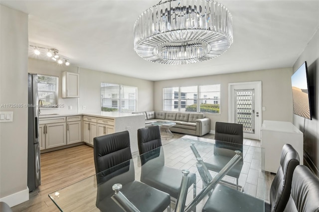 dining area with sink, a chandelier, and light wood-type flooring