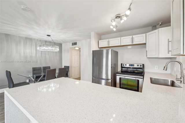 kitchen with sink, appliances with stainless steel finishes, white cabinetry, hanging light fixtures, and light stone countertops