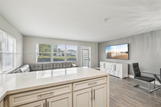 kitchen with light stone counters, cream cabinets, and light hardwood / wood-style flooring