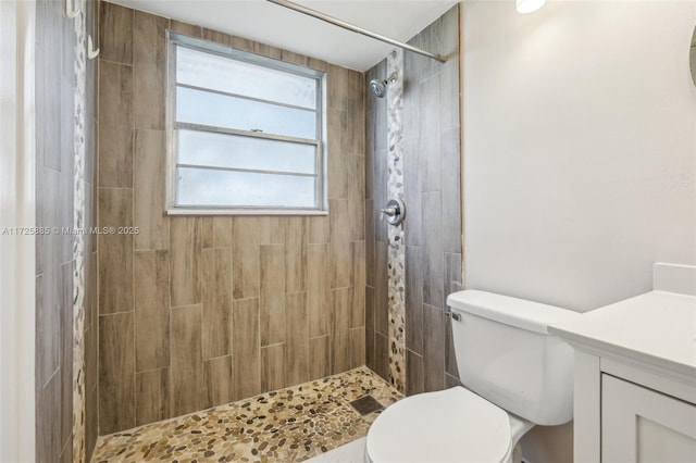 bathroom with vanity, tiled shower, and toilet