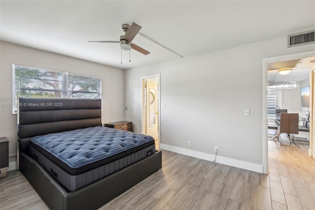 bedroom with ceiling fan, light wood-type flooring, and ensuite bath