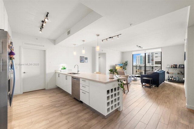 kitchen with pendant lighting, white cabinetry, stainless steel appliances, sink, and kitchen peninsula