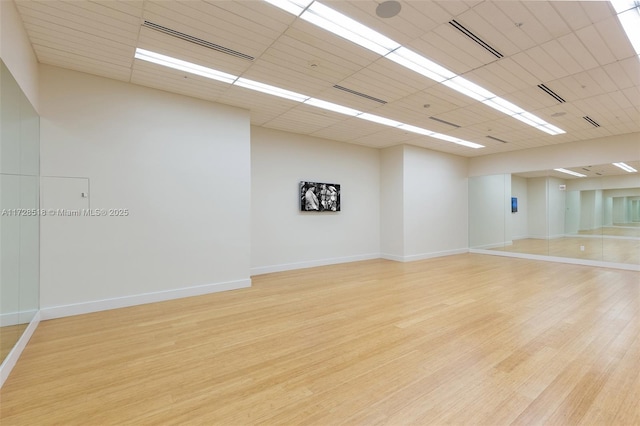 empty room featuring light wood-type flooring and a paneled ceiling