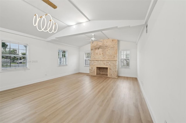 unfurnished living room featuring a healthy amount of sunlight, lofted ceiling with beams, a premium fireplace, and light hardwood / wood-style floors