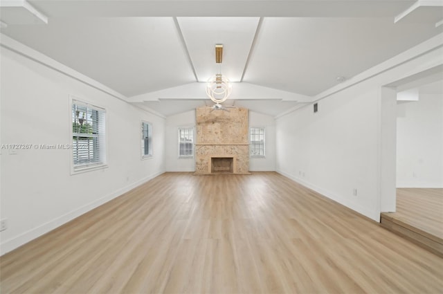 unfurnished living room featuring vaulted ceiling, a fireplace, and light hardwood / wood-style flooring