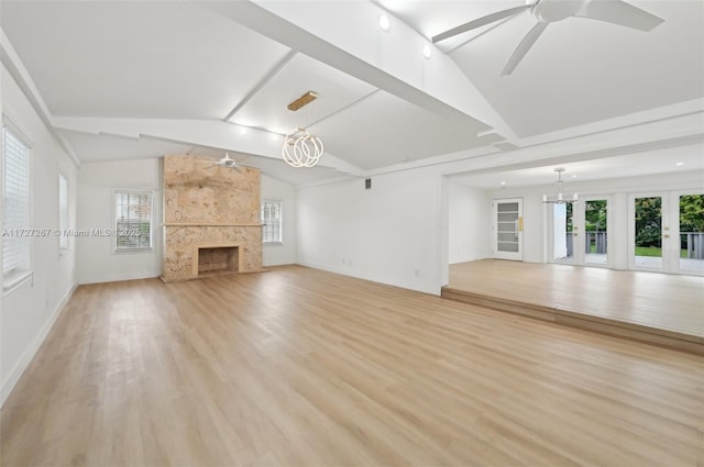 unfurnished living room with vaulted ceiling, a wealth of natural light, light hardwood / wood-style flooring, a high end fireplace, and ceiling fan with notable chandelier