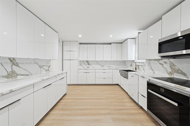 299 S Biscayne River Dr, Miami, FL 33169 - kitchen featuring black appliances, modern cabinets, white cabinetry, a sink, and light wood finished floors