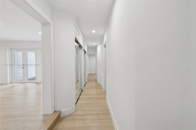 hall with light wood-type flooring and french doors