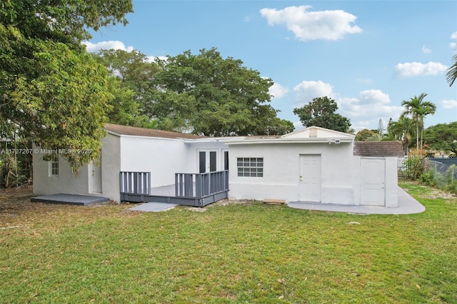 back of property featuring a wooden deck and a yard