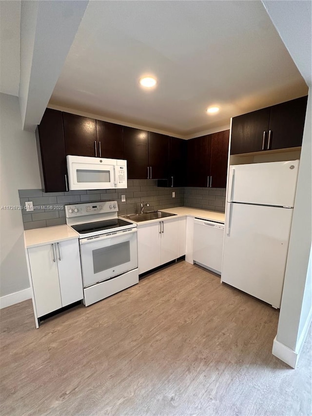 kitchen featuring tasteful backsplash, white appliances, dark brown cabinets, light hardwood / wood-style flooring, and sink