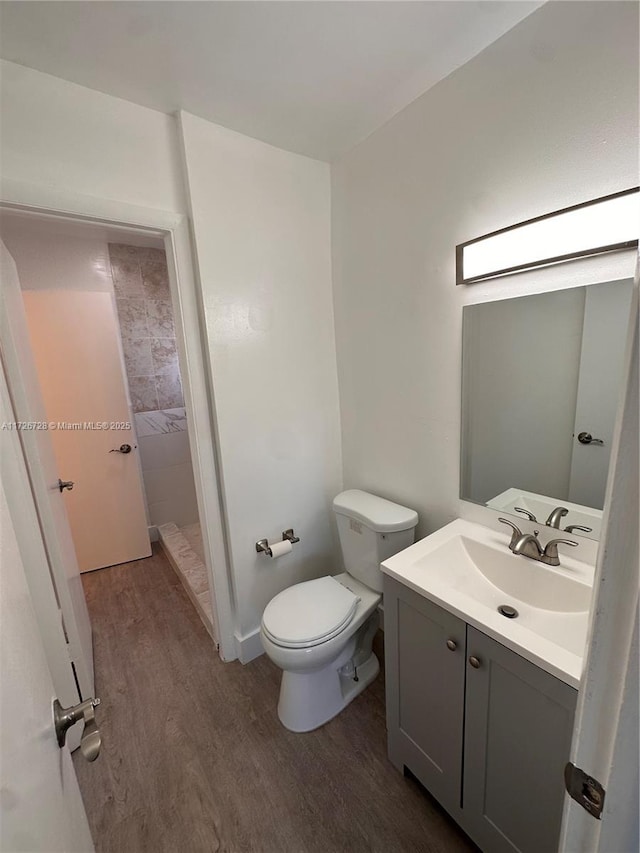 bathroom with toilet, walk in shower, hardwood / wood-style floors, and vanity