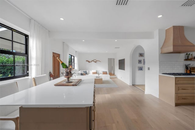 kitchen with a kitchen breakfast bar, premium range hood, plenty of natural light, and backsplash