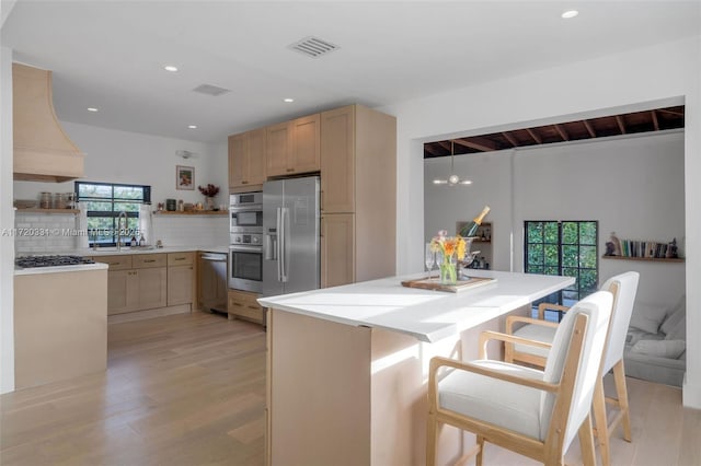 kitchen featuring custom exhaust hood, decorative backsplash, light brown cabinets, and stainless steel appliances