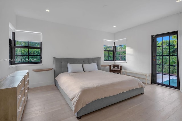 bedroom featuring access to exterior, multiple windows, and light hardwood / wood-style flooring