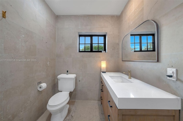 bathroom with toilet, vanity, and tile walls