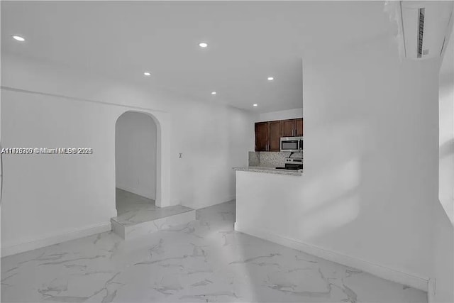 kitchen with arched walkways, recessed lighting, stainless steel appliances, marble finish floor, and tasteful backsplash