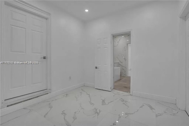 interior space featuring recessed lighting, marble finish floor, and baseboards