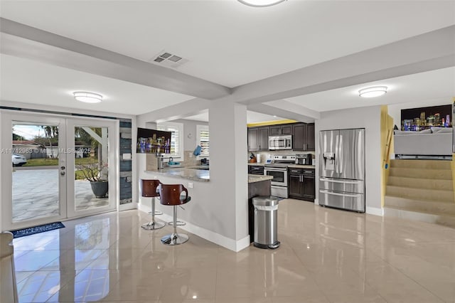 kitchen featuring a breakfast bar area, stainless steel appliances, a healthy amount of sunlight, and dark brown cabinetry