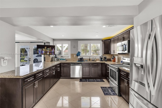 kitchen featuring light stone countertops, stainless steel appliances, tasteful backsplash, sink, and kitchen peninsula