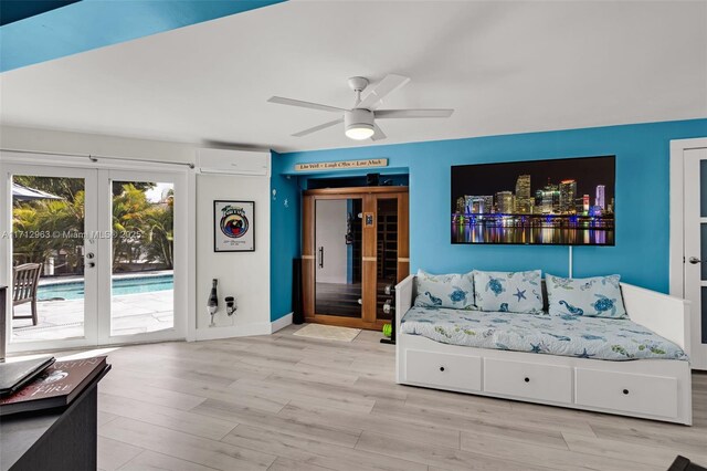 living room with ceiling fan, a wall mounted AC, french doors, and light hardwood / wood-style flooring