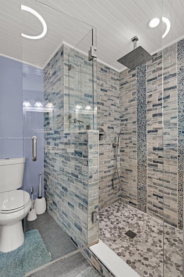 bathroom with toilet, a shower with door, and tile patterned flooring