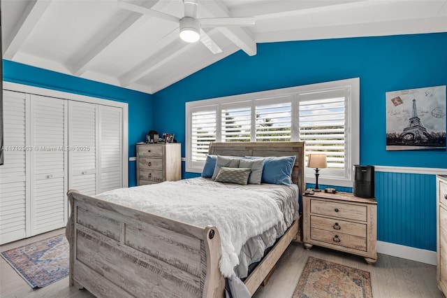 bedroom featuring light wood-type flooring, ceiling fan, a closet, and lofted ceiling with beams