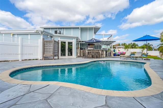 view of swimming pool featuring french doors, an outdoor bar, and a patio