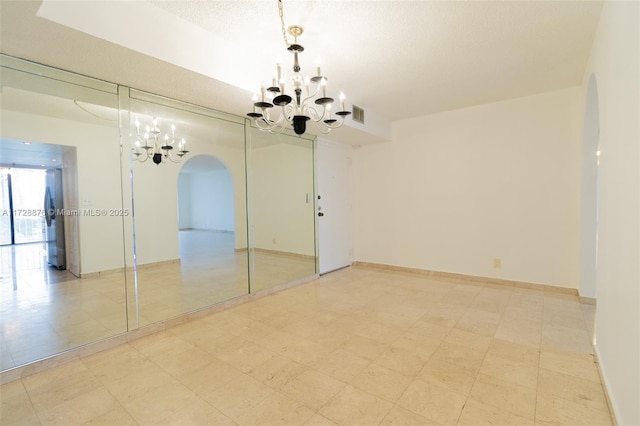 unfurnished room with a textured ceiling and a notable chandelier