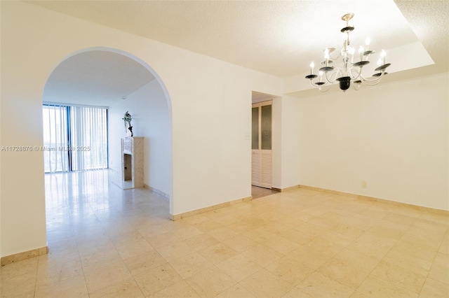 unfurnished room with a notable chandelier, floor to ceiling windows, and a textured ceiling