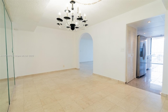 empty room with a textured ceiling, an inviting chandelier, and a wall of windows