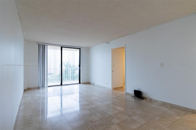 unfurnished room featuring floor to ceiling windows and a textured ceiling