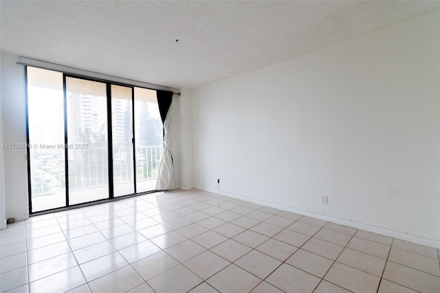 unfurnished room featuring floor to ceiling windows, a textured ceiling, and light tile patterned floors